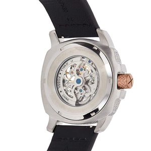 Close-up rear view of a wristwatch with a silver-toned case, transparent back showing an exposed mechanical movement, and a black strap on a white background.
