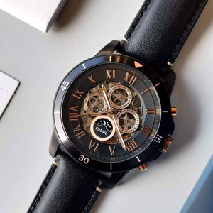 Black wristwatch with a detailed face on a light gray surface