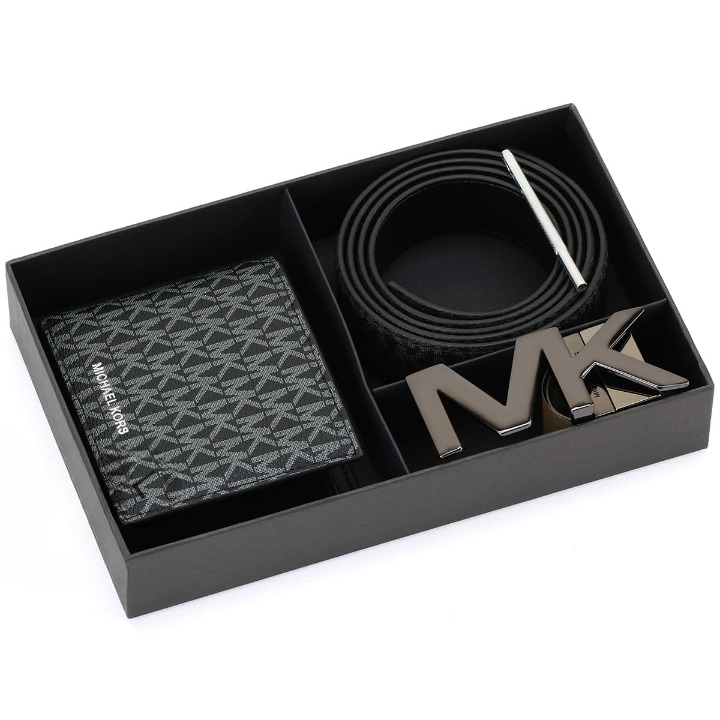 Top-down view of a Michael Kors men's black gift set inside its presentation box, featuring a monogram wallet, coiled reversible belt, rotating MK buckle, and sizing tool