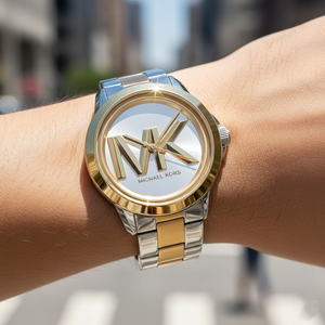 Extreme close-up of Michael Kors MK7319 showing raised gold MK logo on silver dial