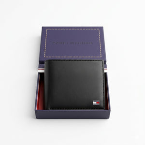 Top-down studio photograph of the Tommy Hilfiger mirror original leather wallet and card case set neatly placed inside its open premium navy gift box