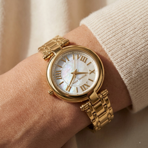 Close up of Michael Kors Lennox MK01083 women's quartz battery watch on wrist showing white mother of pearl dial and gold metal bracelet