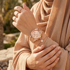 Elegant woman wearing Michael Kors Raquel MK4688 women's quartz battery watch with architectural rose gold-tone case luxury style watch