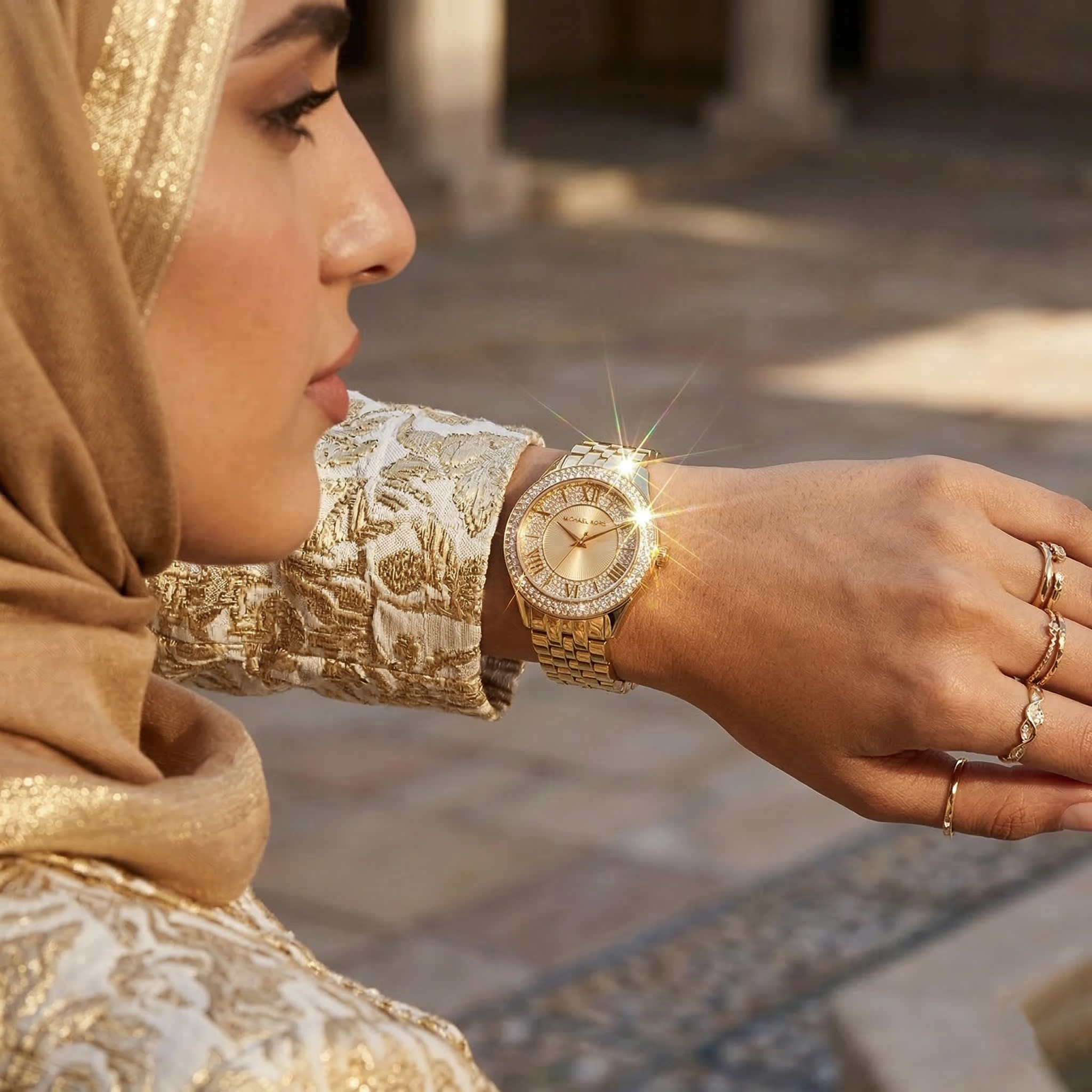 Elegant woman wearing Michael Kors Harlowe MK4709 women's quartz battery watch with gold-tone case and brilliant crystal bezel