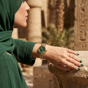 Elegant woman wearing Michael Kors Lennox MK4892 women's quartz battery watch with gold-tone case and emerald green mother of pearl dial