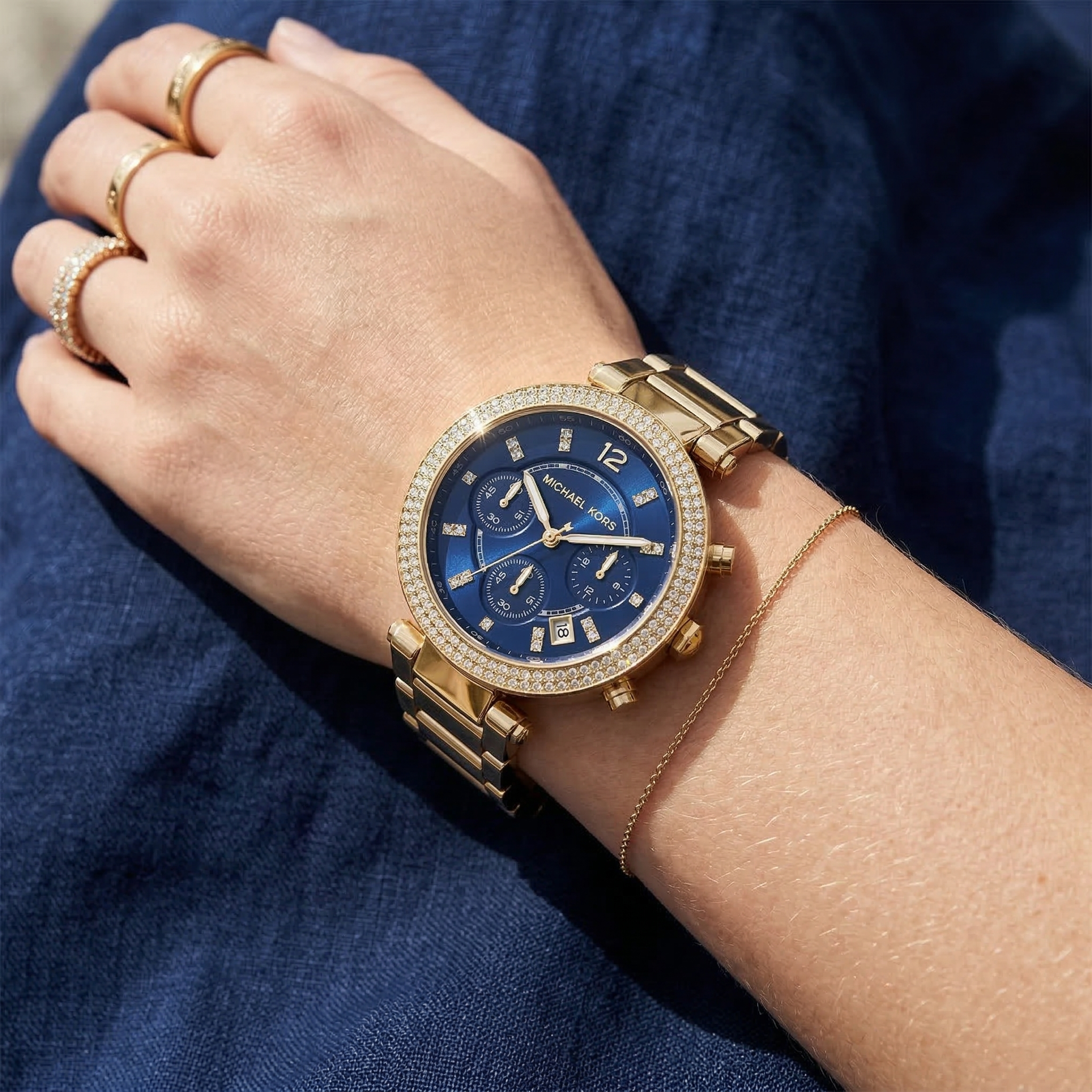 Close up of Michael Kors Parker MK6262 women's quartz battery watch on wrist showing navy blue sunray dial and gold metal bracelet