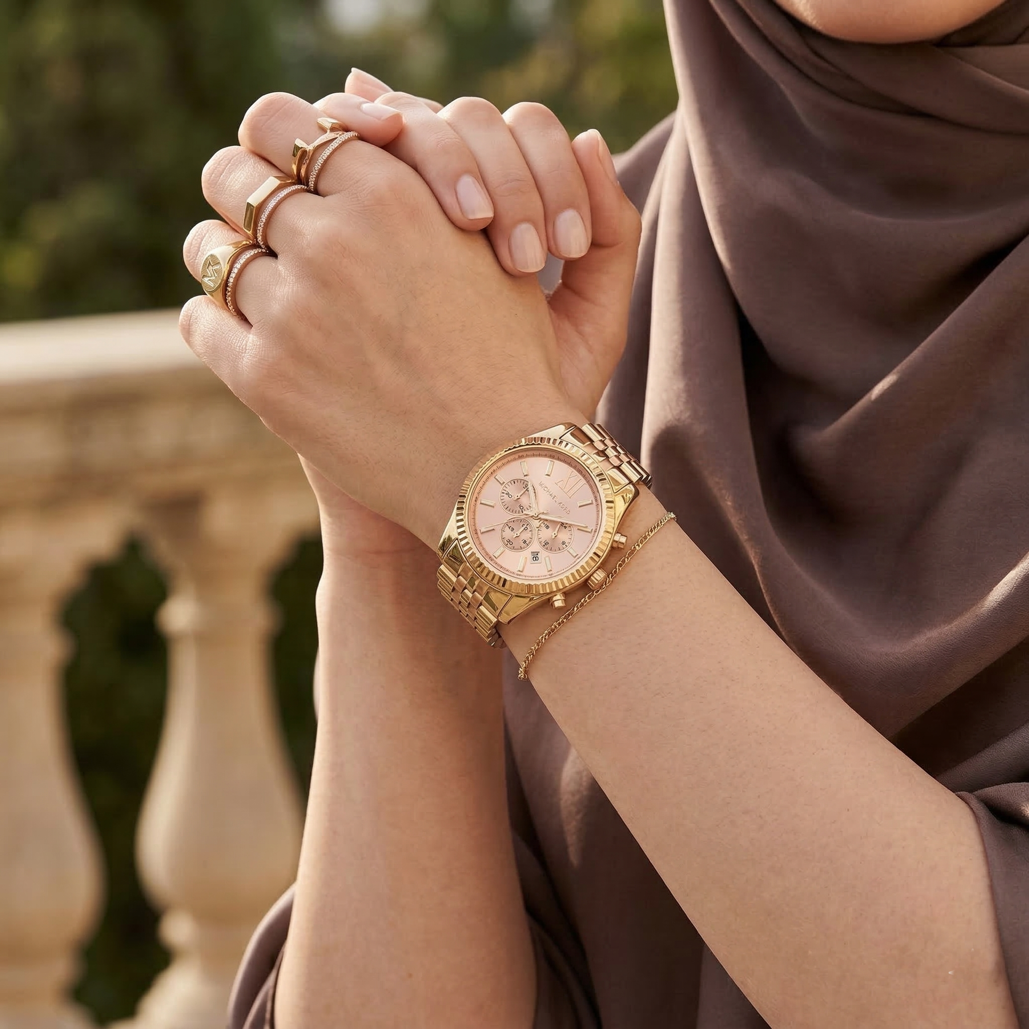 Elegant woman wearing Michael Kors Lexington MK6473 women's quartz battery watch with gold-tone case and luxury rose gold dial