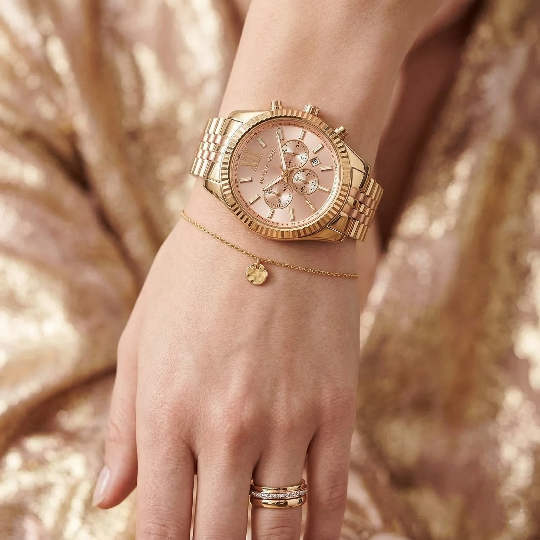 Close up of Michael Kors Lexington MK6473 women's quartz battery watch on wrist showing rose gold sunray dial and two-tone metal bracelet