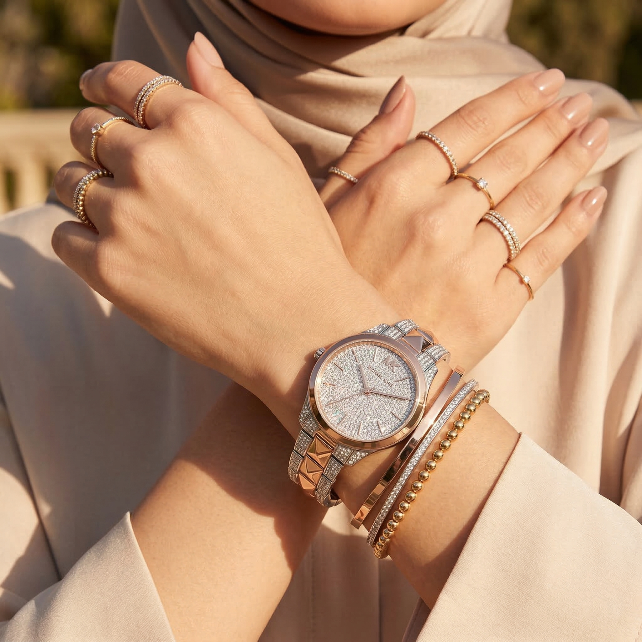 Elegant woman wearing Michael Kors Runway Mercer MK6716 women's quartz battery watch with two-tone silver and rose gold case and brilliant pavé dial