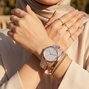 Elegant woman wearing Michael Kors Runway Mercer MK6716 women's quartz battery watch with two-tone silver and rose gold case and brilliant pavé dial