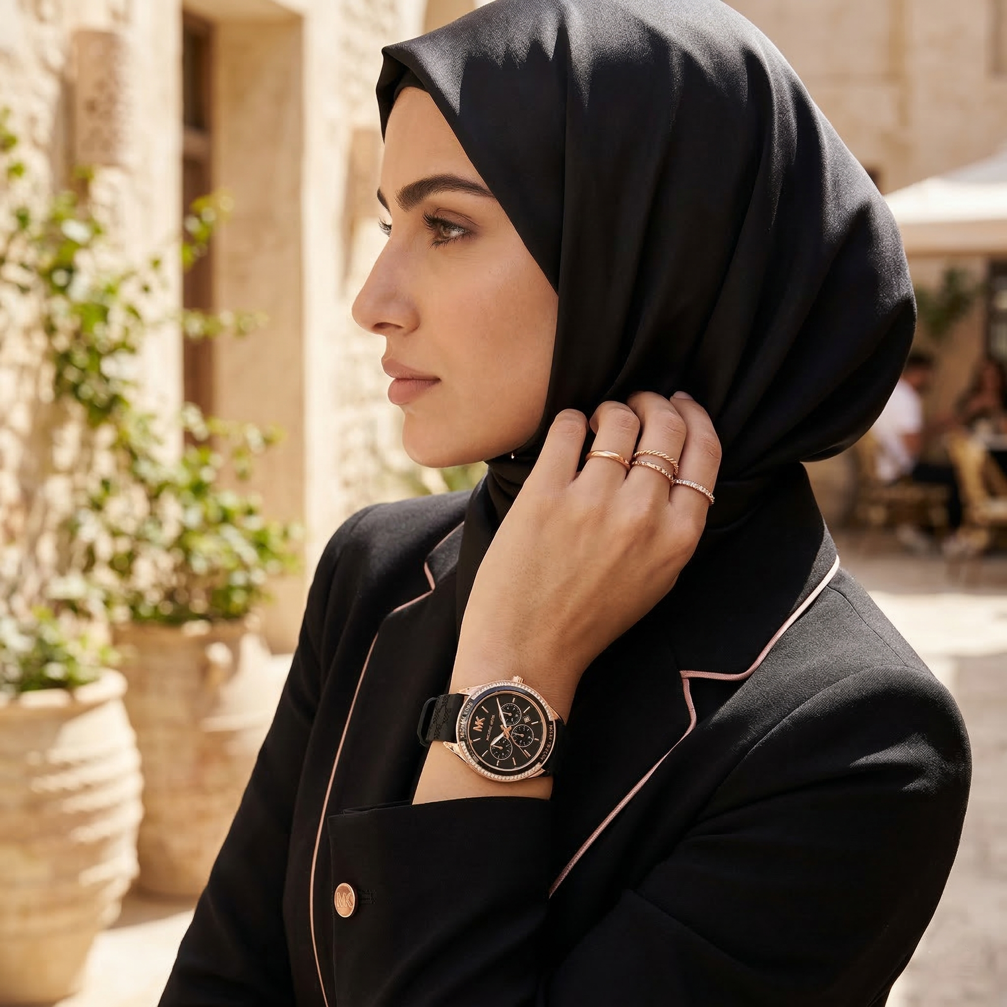 Elegant woman wearing Michael Kors Jessa MK7266 women's quartz battery watch with rose gold-tone case and sporty black rubber strap