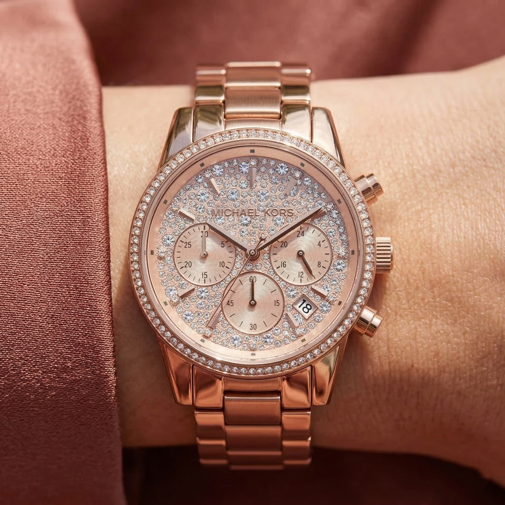 Close up of Michael Kors Ritz MK7302 women's quartz battery watch on wrist showing full pavé crystal dial and rose gold metal bracelet