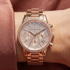 Close up of Michael Kors Ritz MK7302 women's quartz battery watch on wrist showing full pavé crystal dial and rose gold metal bracelet