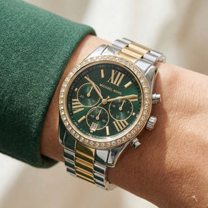 Elegant woman wearing Michael Kors Lexington MK7303 women's quartz battery watch with two-tone case and luxury green dial