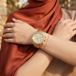 Elegant woman wearing Michael Kors Parker MK7310 women's quartz battery watch with gold-tone case and brilliant pavé dial