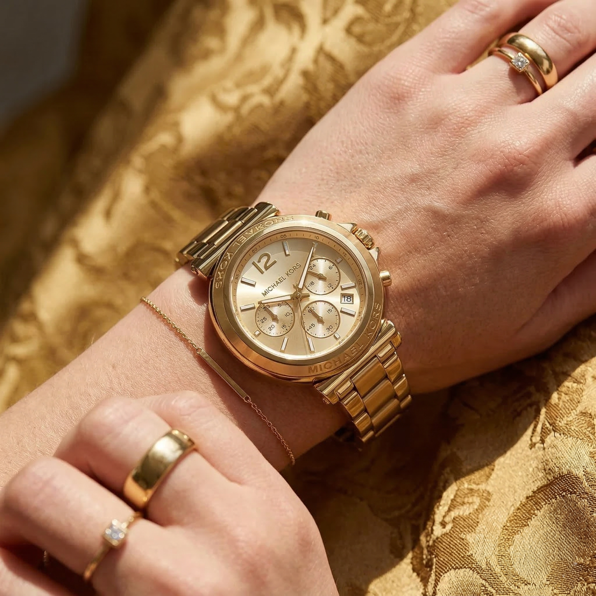 Close up of Michael Kors Maren MK7493 women's quartz battery watch on wrist showing gold sunray dial and gold metal bracelet