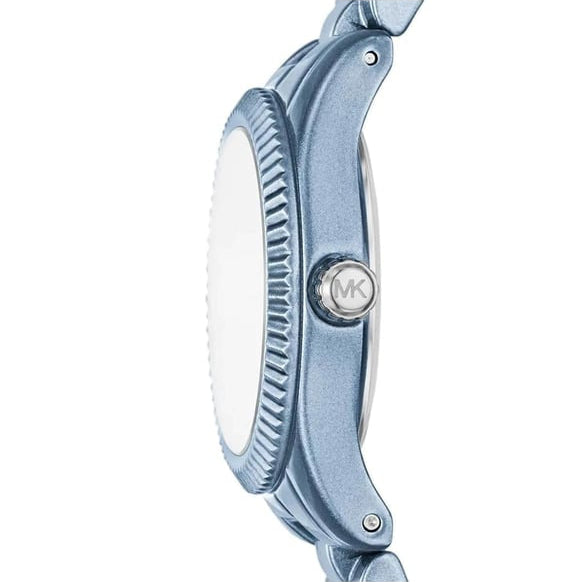 Close-up side view of a Michael Kors watch with a metallic blue case, textured bezel, and silver MK logo on the crown, set against a plain white background.