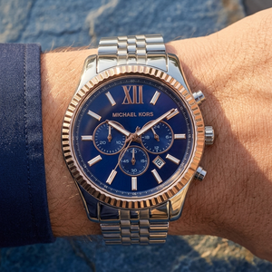 Close up of Michael Kors Lexington MK8689 men's quartz battery watch on wrist showing navy blue sunray dial and rose gold bezel contrast