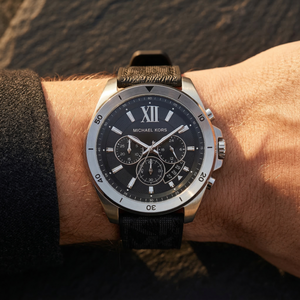 Close up of Michael Kors Brecken MK8850 men's quartz battery watch on wrist showing black textured dial and black rubber strap