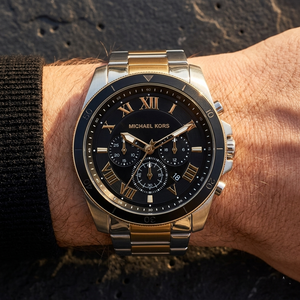 Close up of Michael Kors Alek MK8901 men's quartz battery watch on wrist showing black sunray dial and two-tone metal bracelet