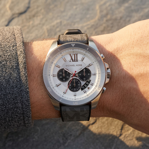 Close up of Michael Kors Brecken MK8922 men's quartz battery watch on wrist showing silver sunray dial and grey rubber strap