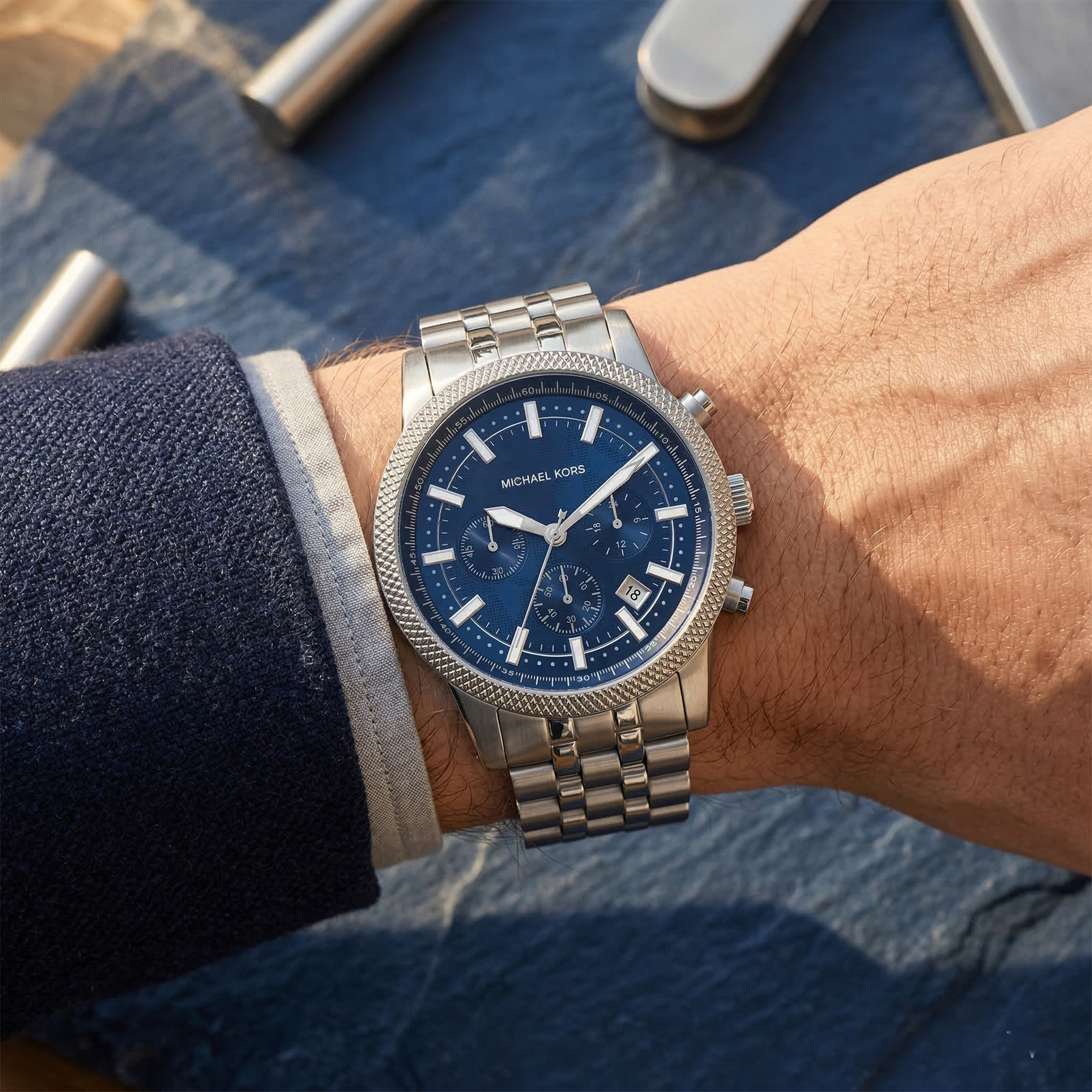 Close up of Michael Kors Hutton MK8952 men's quartz battery watch on wrist showing blue textured dial and silver metal bracelet