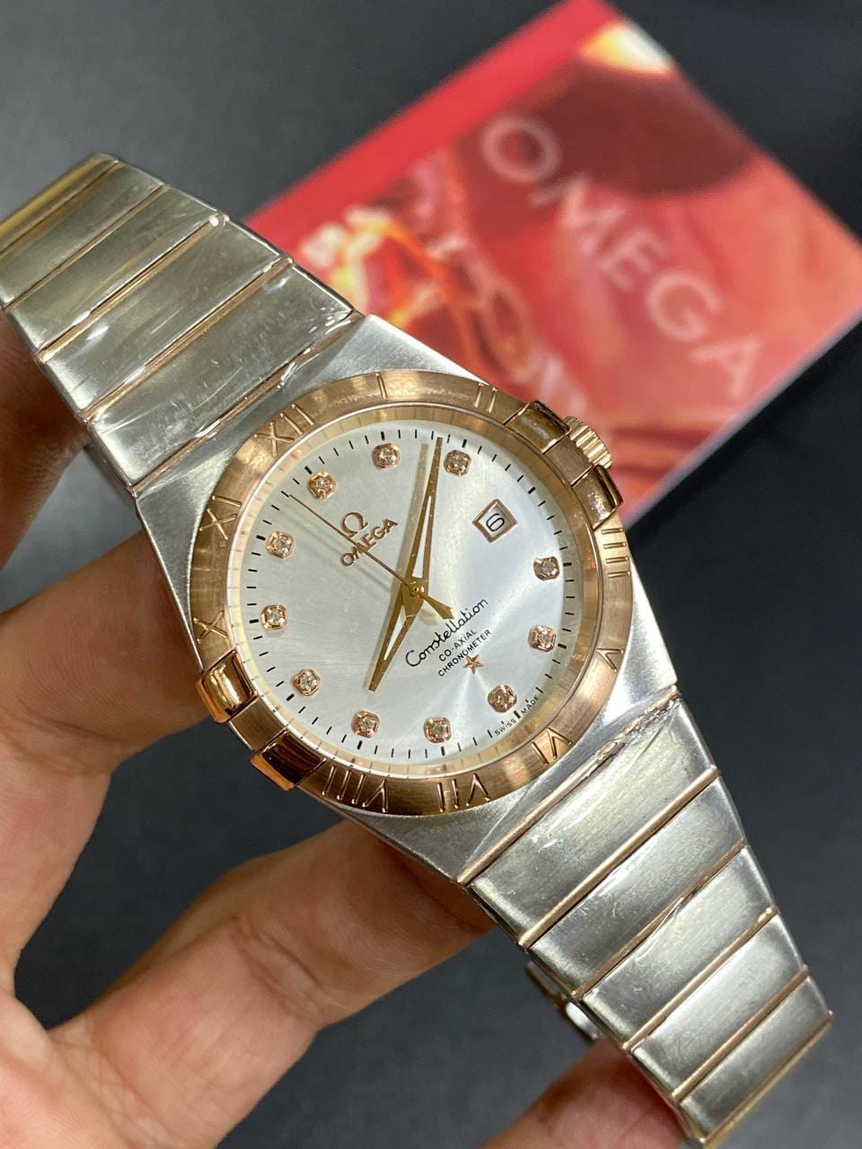 Omega Constellation 123.20.38.21.52.001 men's automatic watch, 38mm two-tone stainless steel and rose gold-tone case, silver dial, Roman numeral bezel, two-tone rose gold bracelet – in-hand view