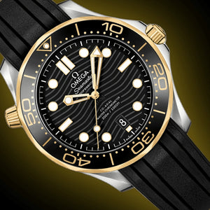 Omega Seamaster Diver 300M men's automatic watch, 42mm steel and yellow gold case, black dial, black rubber strap – dial close-up on dark background