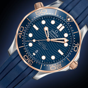 Omega Seamaster Diver 300M men's automatic watch, 42mm steel and rose gold case, blue dial, blue rubber strap – dial angle on dark background