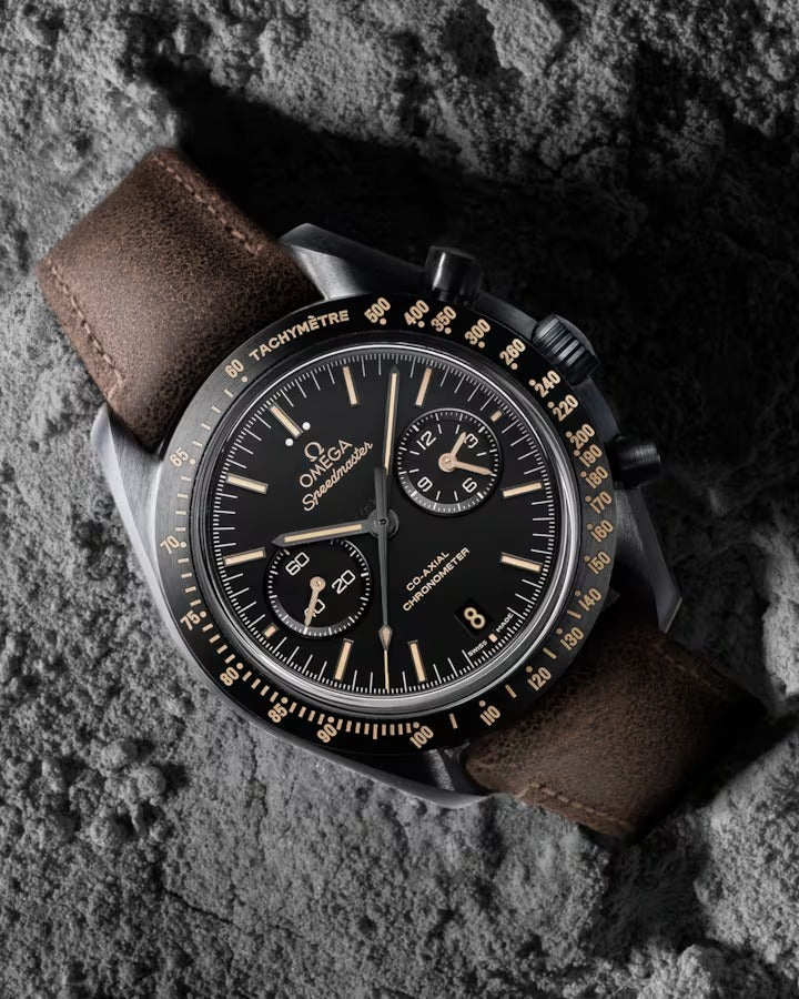 Omega Speedmaster Dark Side of the Moon men's chronograph watch, 43mm black case, black dial, tan leather strap – lifestyle view