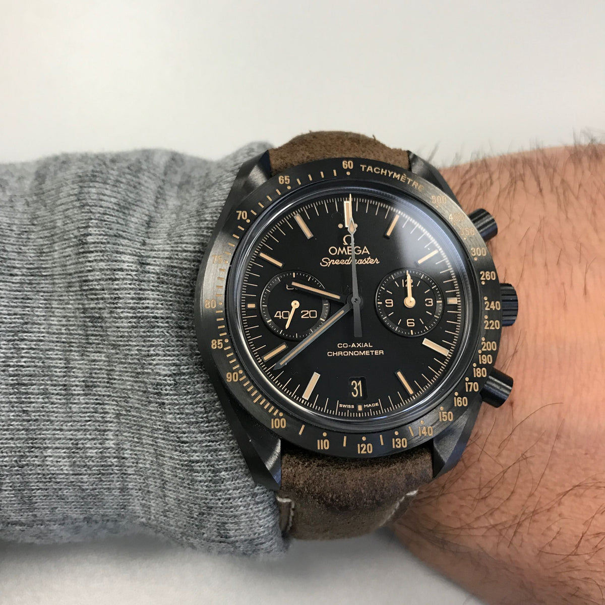 Omega Speedmaster Dark Side of the Moon men's chronograph watch, 43mm black case, black dial, tan leather strap – on wrist close-up