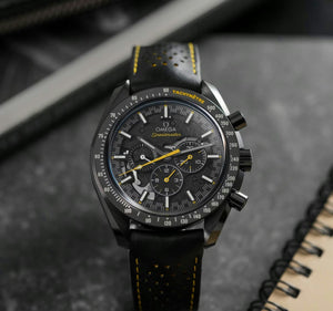 Omega Speedmaster Dark Side of the Moon Style men's chronograph watch, 45mm black case, black dial with yellow accents, black leather strap – angle view on dark background