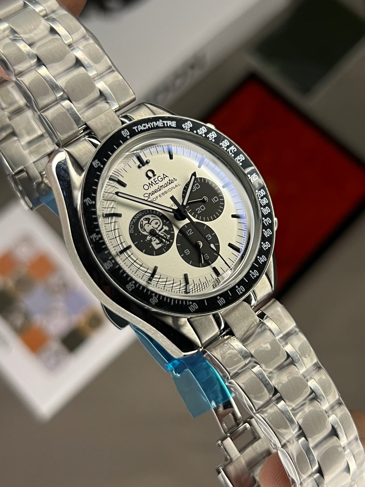 Omega Speedmaster Snoopy Award men's chronograph watch, 42mm stainless steel case, white dial with black subdials, steel bracelet – angle view in box