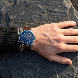 Close up of Maserati Competizione R8851100004 men's quartz battery watch on wrist showing blue honeycomb dial and brown leather strap