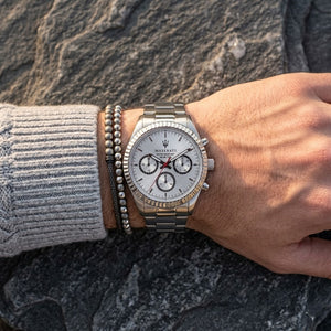 Close up of Maserati Competizione R8853100018 men's quartz battery watch on wrist showing silver multi-function dial and silver metal bracelet