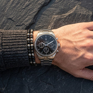 Close up of Maserati Competizione R8853100023 men's quartz battery watch on wrist showing black multi-function dial and silver metal bracelet