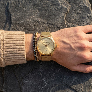 Close up of Maserati Epoca R8853118003 men's quartz battery watch on wrist showing gold sunray dial and gold mesh metal strap