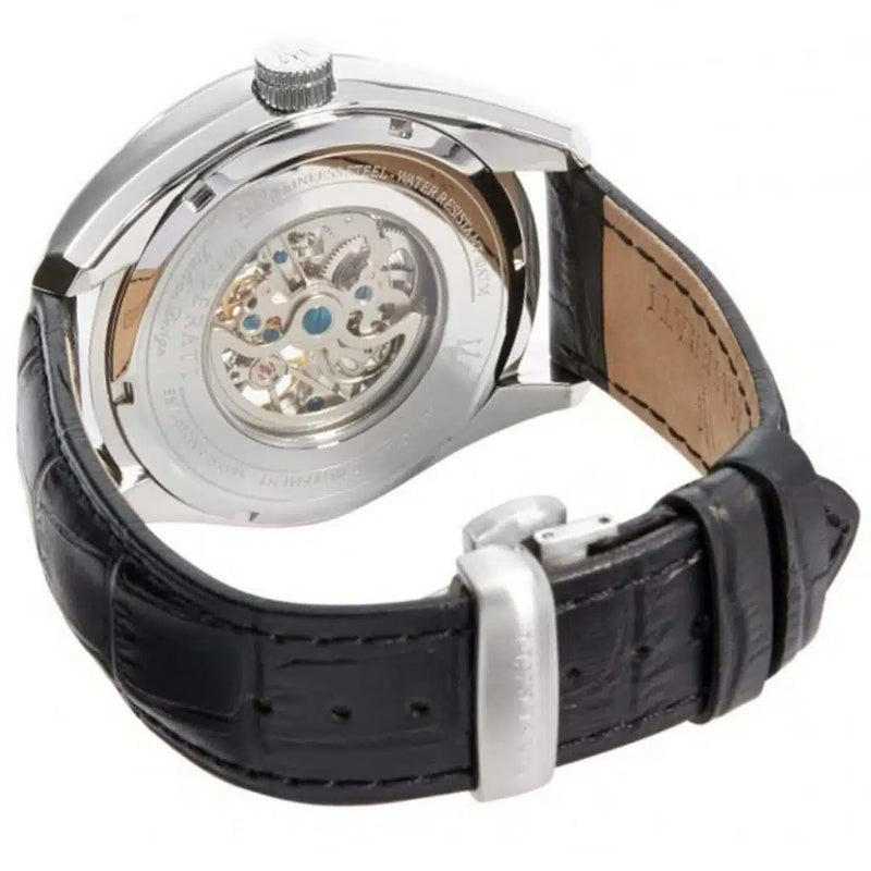 Close-up of the back of a wristwatch showing a silver-tone case with a transparent dial cover and visible mechanical movement, attached to a black alligator leather strap with a silver buckle.