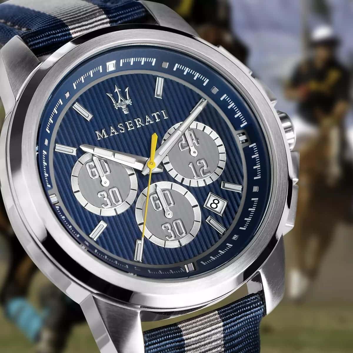 Maserati watch with blue face and strap against a blurred equestrian background