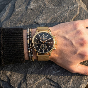 Close up of Maserati Epoca R8873618007 men's quartz battery watch on wrist showing black sunray dial and gold mesh metal strap