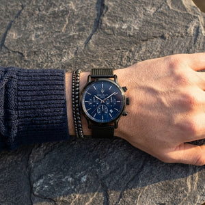 Close up of Maserati Epoca R8873618008 men's quartz battery watch on wrist showing blue sunray dial and black mesh strap