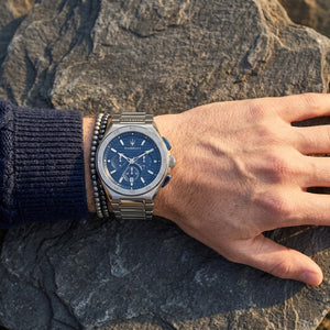 Close up of Maserati Triconic R8873639001 men's quartz battery watch on wrist showing blue striped dial and integrated silver metal bracelet