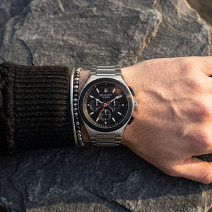 Close up of Maserati Triconic R8873639002 men's quartz battery watch on wrist showing black striped dial and silver metal bracelet