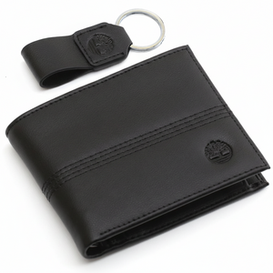 Top-down view of a Timberland men's gift set featuring a black genuine leather bifold wallet with an embossed tree logo and a matching leather keychain