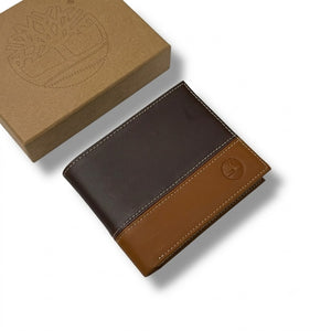 Live front view smartphone photograph of the Timberland smooth dark and light brown leather bifold wallet highlighting the round silver metal tree hardware logo corner accent