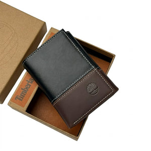 Live smartphone photograph of the Timberland mirror original two-tone black and brown leather trifold wallet with silver tree logo resting inside the custom black box tray