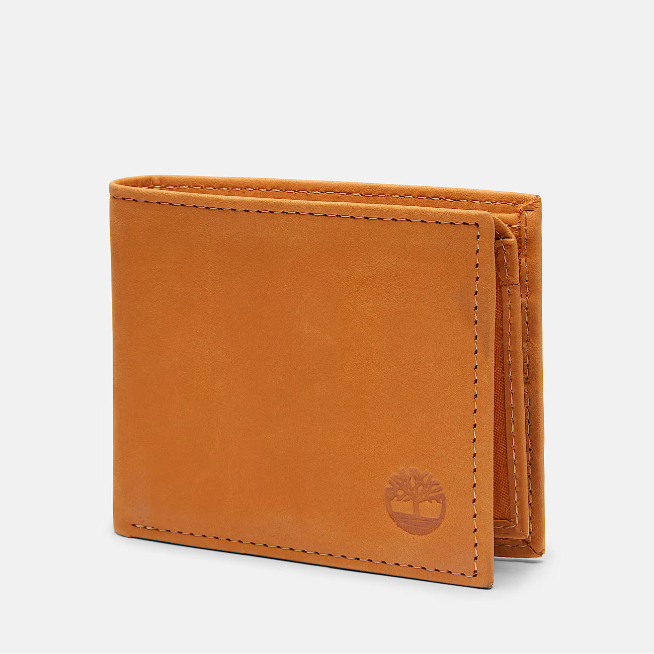 Studio product photograph of the Timberland mirror original wheat tan smooth leather bifold wallet highlighting the round silver metal tree hardware logo corner accent