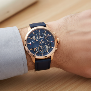 Close up shot of Tommy Hilfiger 1710475 watch on wrist with a matching blue background showing the skeleton dial
