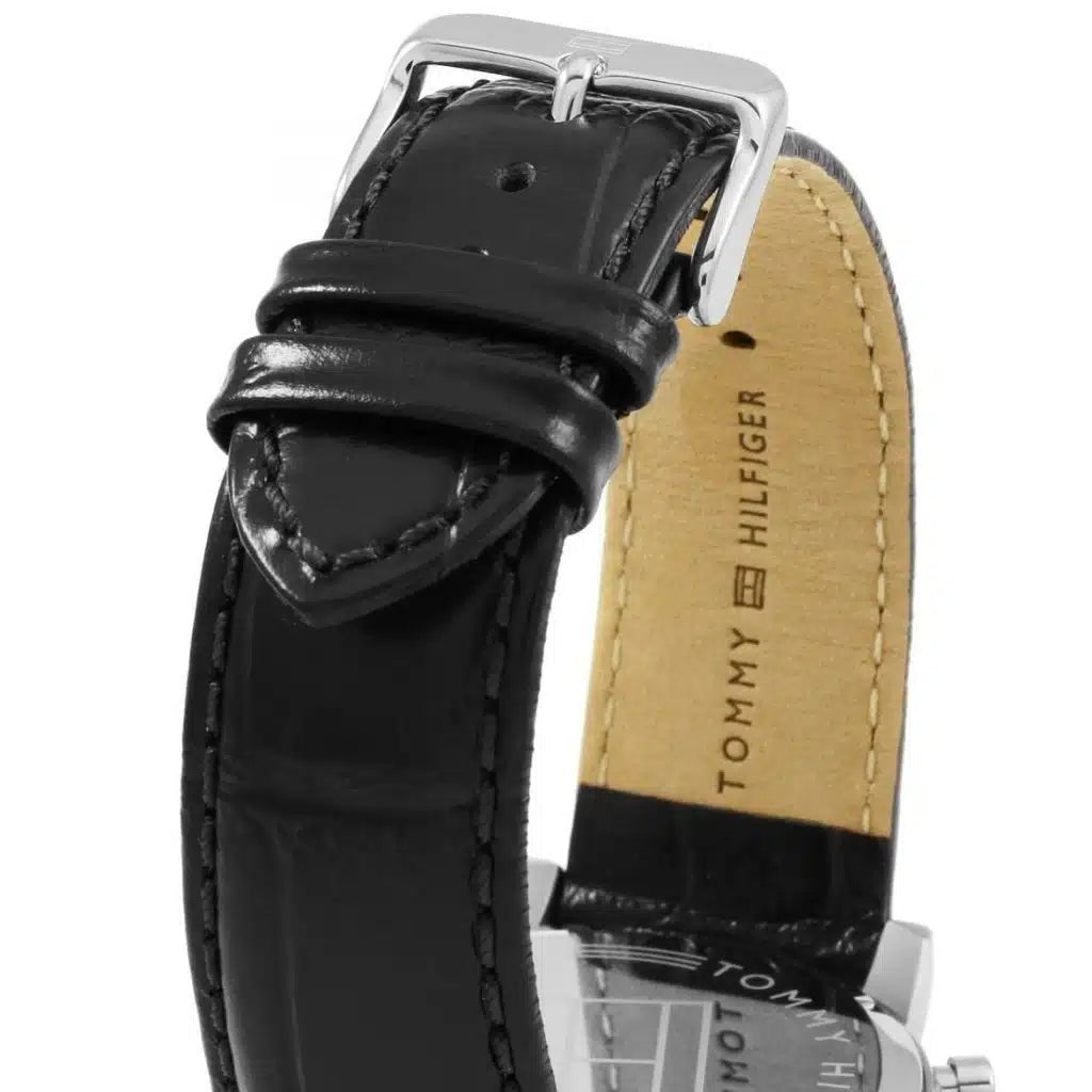 Left side perspective of the silver case and detailed stitching on the black leather strap of the Tommy Hilfiger watch
