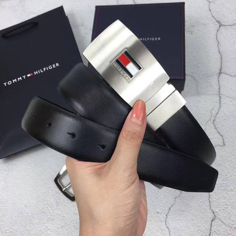 Close up detail of Tommy Hilfiger silver plaque belt buckle with flag logo and embossed genuine leather branding